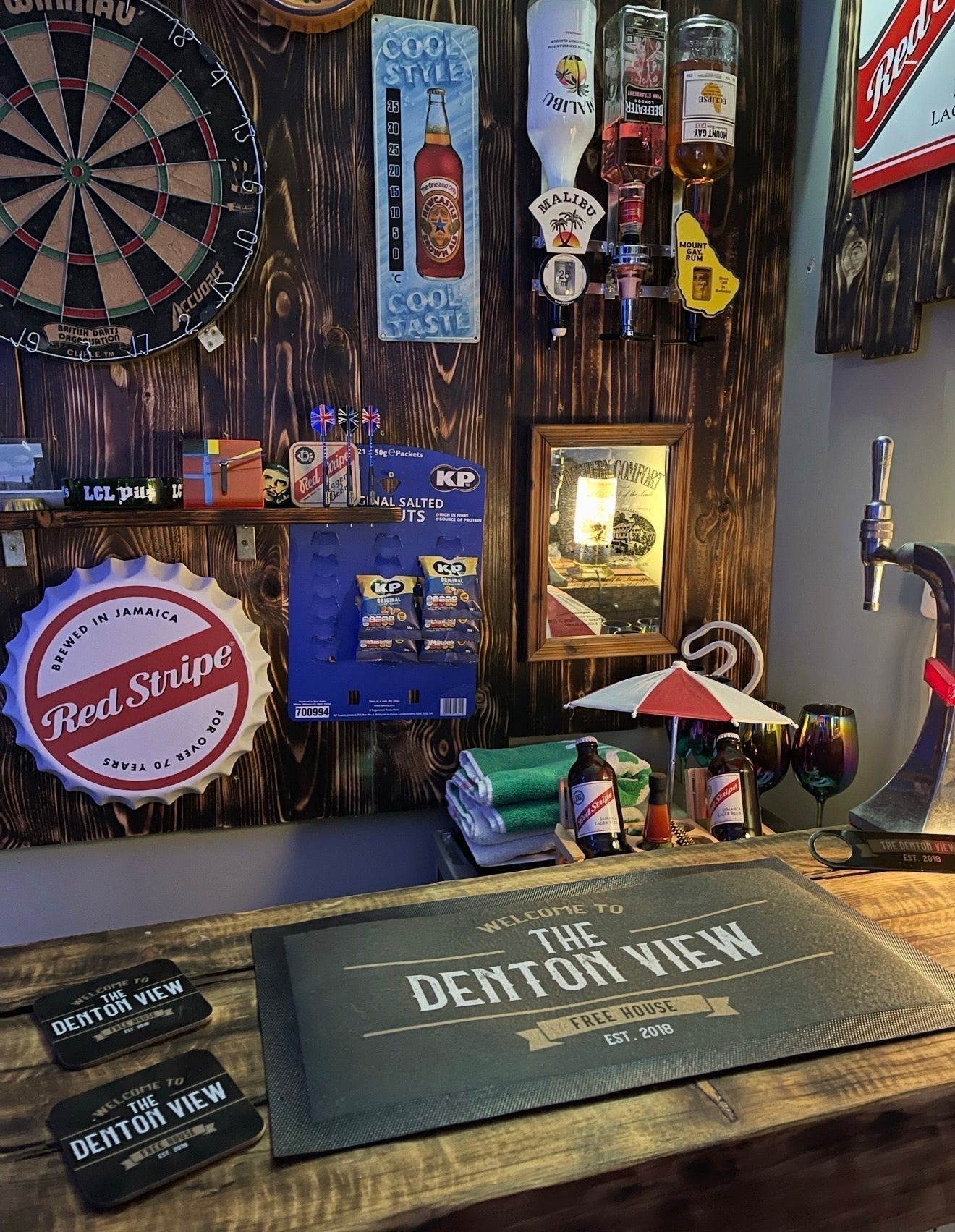 Personalised home bar set on a wooden bar, featuring a custom bar mat, matching coasters and accessories displayed in a home bar setting.
