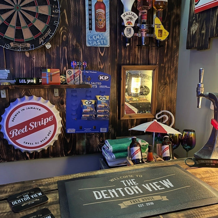 Personalised home bar set on a wooden bar, featuring a custom bar mat, matching coasters and accessories displayed in a home bar setting.
