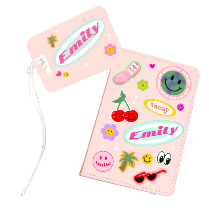 A pink personalised passport holder and matching luggage tag set featuring colourful stickers and the name Emily printed in a retro-style font. Both items include cheerful travel-themed designs such as cherries, palm trees, and smiley icons.