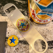 Bottle opener with a badge and a bottle cap on a countertop next to a Crown Royal bottle.