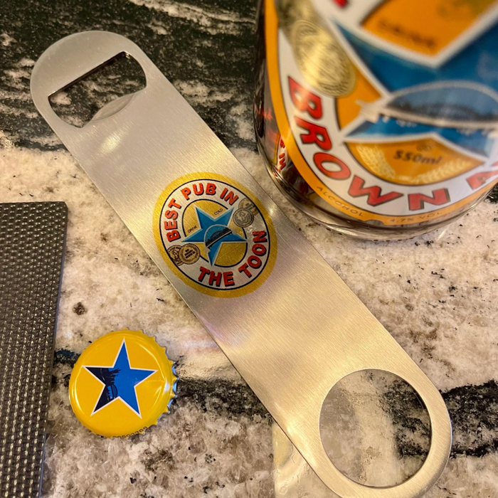 Bottle opener with a badge and a bottle cap on a countertop next to a Crown Royal bottle.