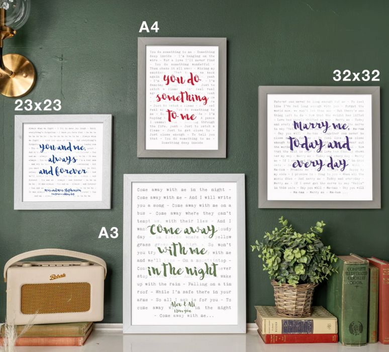 Framed prints with romantic text on a wall with books and a radio.