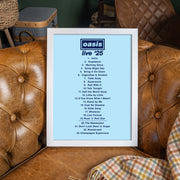 Framed list of songs from 'oasis live '25' on a light blue background, placed on a brown leather couch.