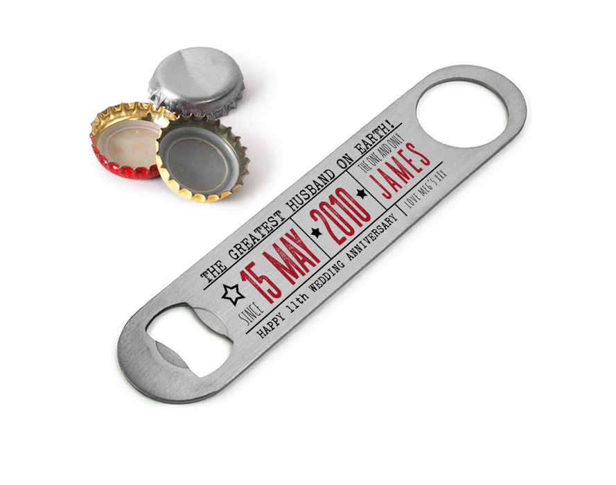 Personalised anniversary bar blade bottle opener engraved with date and name, shown flat on a white surface with silver and gold bottle caps.