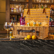 Personalised gin hamper gift set featuring engraved glasses, Whitley Neill gin, Fever-Tree tonics, lemons, and a wicker basket with leather straps, displayed on a marble bar.