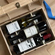 Top view of open wooden wine chest containing three bottles of wine arranged neatly in divided compartments.