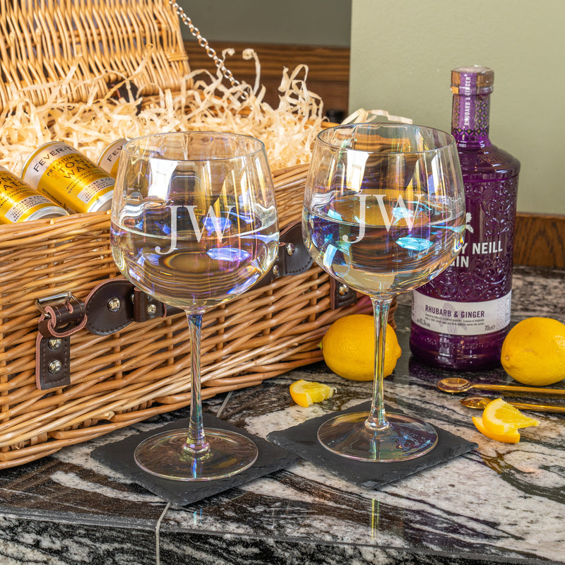 Two personalised gin glasses engraved with “JW,” paired with a wicker hamper filled with Whitley Neill gin, Fever-Tree tonic cans, and lemons.