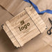 Wooden gift box with engraved text and logo on a textured surface