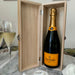 Wooden champagne presentation box displayed upright, open to show a bottle of Veuve Clicquot with champagne flutes beside it.