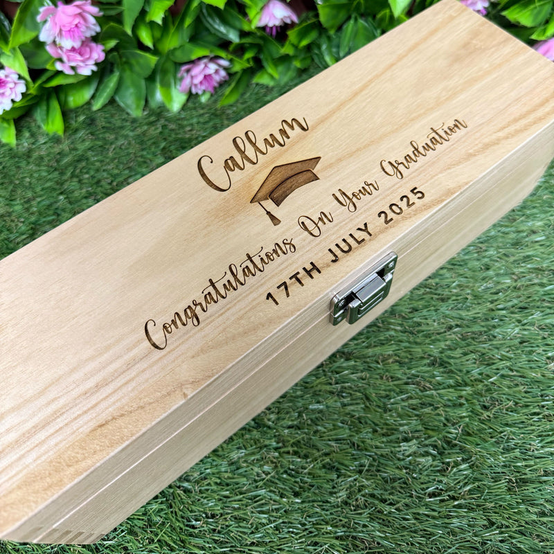 Wooden box with engraved graduation message on grass
