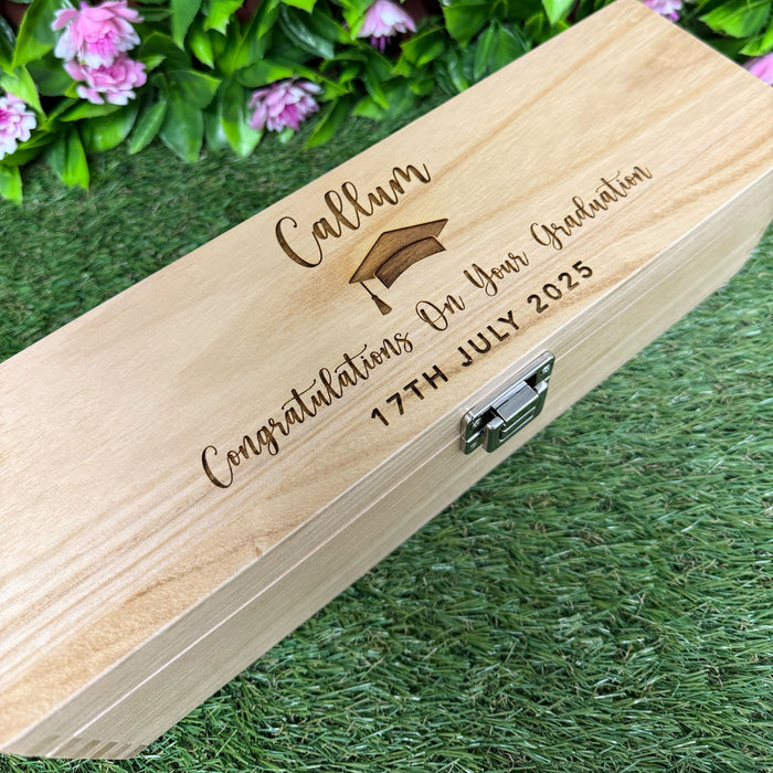 Wooden box with engraved graduation message on grass