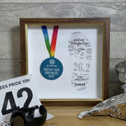 marathon medal inside a dark wood and gold frame