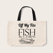 An off-white canvas tote bag with black handles and a black graphic print that reads 'Off My Tits ON FISH & CHIPS' above a fish in a tray illustration, shown on a light beige background.