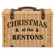 A rectangular woven wicker picnic basket with a dark brown handle and straps, featuring the black printed text 'CHRISTMAS at the RENTONS' on the front, set against a plain white background.