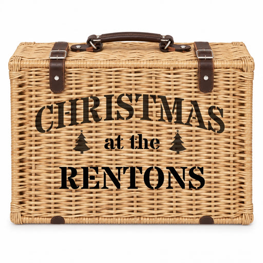 A rectangular woven wicker picnic basket with a dark brown handle and straps, featuring the black printed text 'CHRISTMAS at the RENTONS' on the front, set against a plain white background.