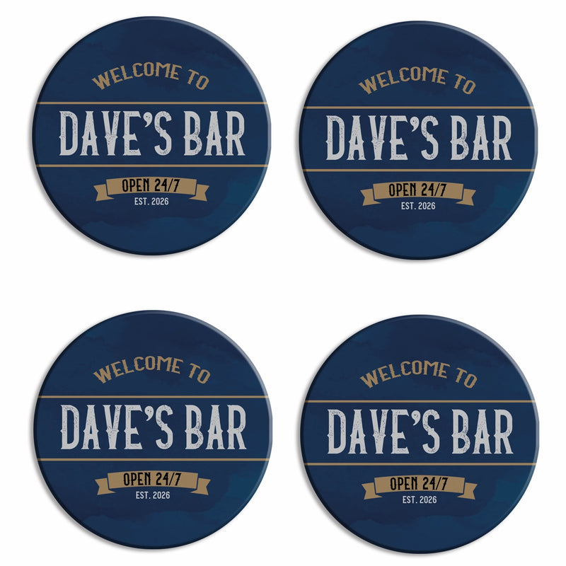 Four round coasters arranged in a 2x2 grid on a white background. Each coaster has a dark navy blue camouflage pattern with gold and white text reading 'WELCOME TO DAVE'S BAR' and 'OPEN 24/7 EST.