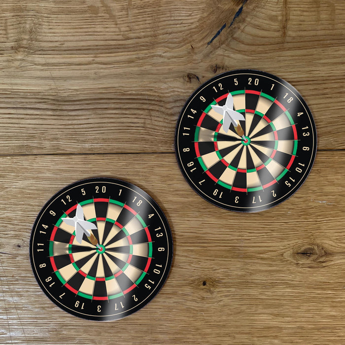 set of two round dartboard-style coasters with dart graphic, placed on a wooden surface.”