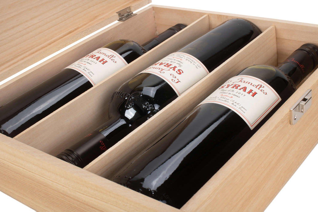 Interior of a wooden wine gift box with three compartments holding Syrah wine bottles.